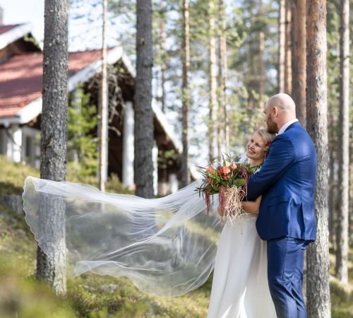 onnellinen hääpari halaa metsämaisemassa